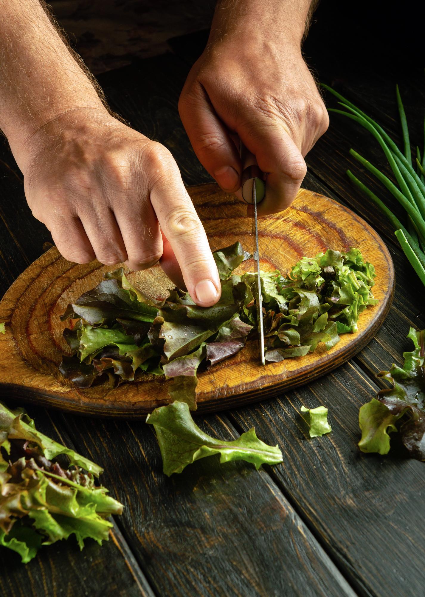 Close-up of hands seasoning a salad